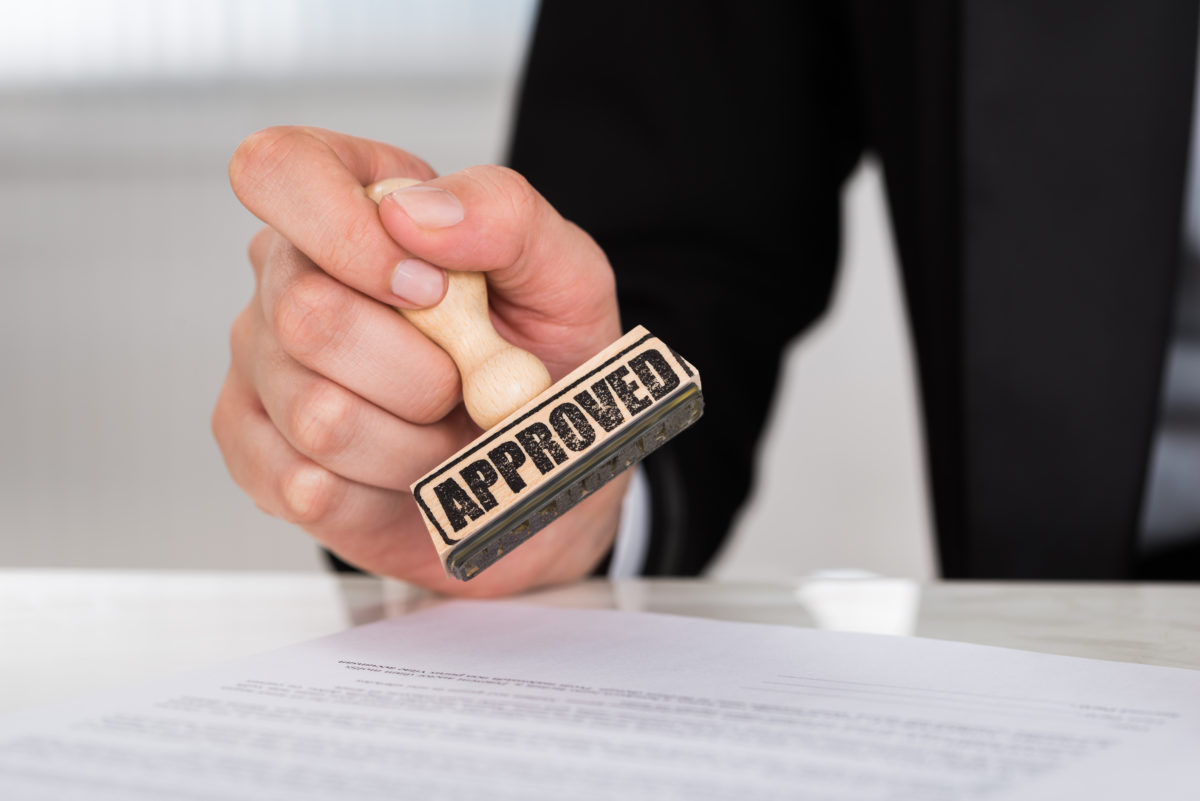 Businesswoman Stamping Approved On Contract Paper At Desk