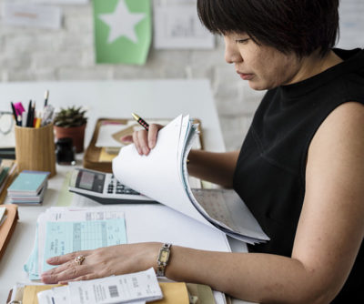 Woman at a desk with a stack of paperwork