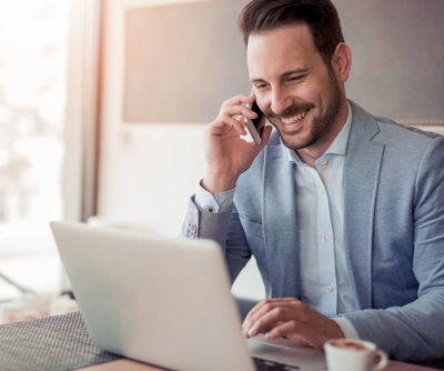 Man smiling in a suit with a phone and a computer