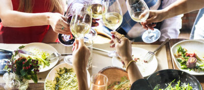 People touching glasses over a table of food