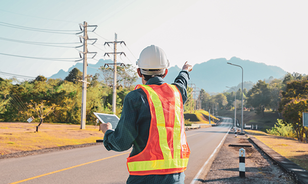 Construction worker holding a tablet and pointing outside