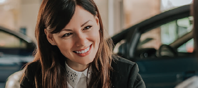 Woman smiling in front of a car